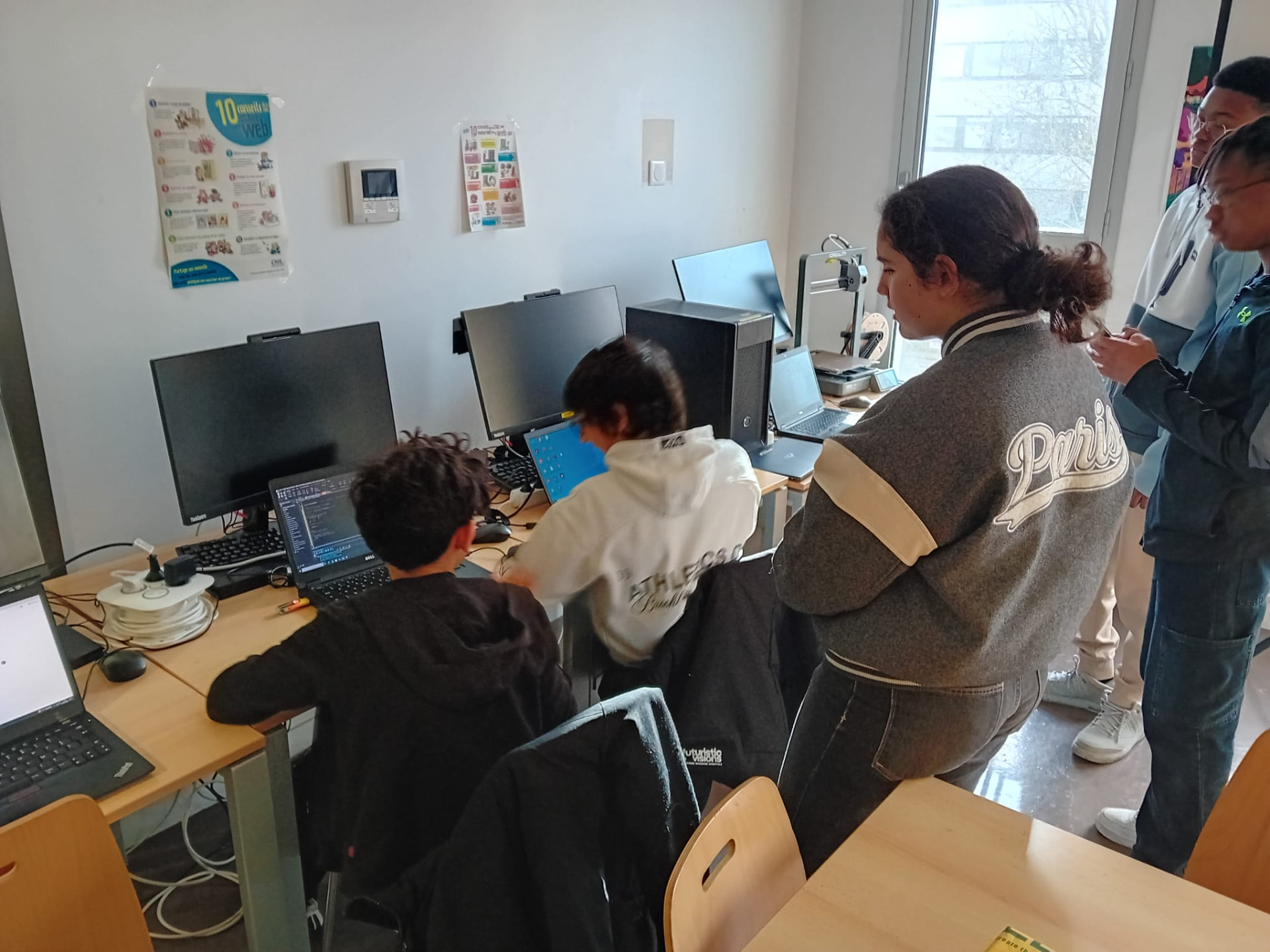 Jeunes en atelier devant les ordinateurs et une imprimante 3D