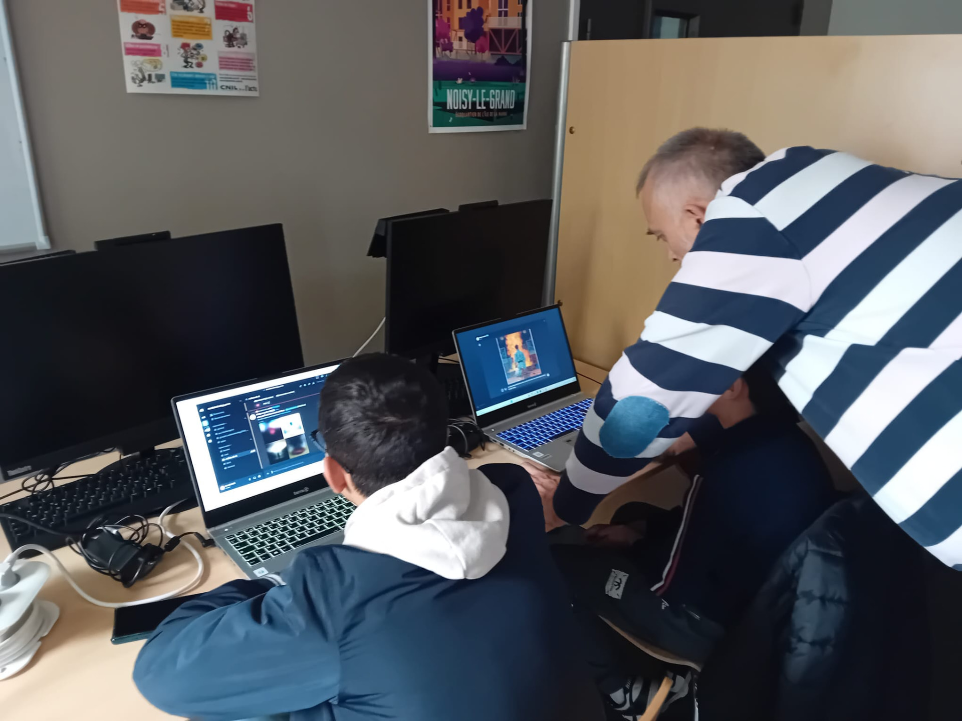Un formateur accompagne un jeune sur ordinateur portable